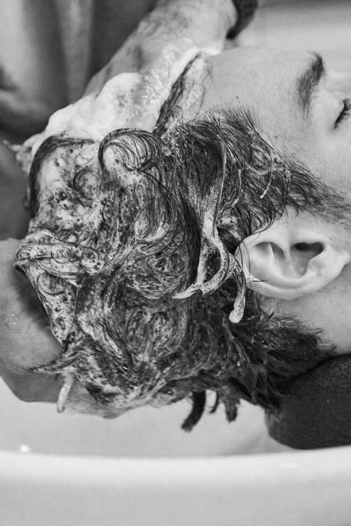 Black-and-white photograph of a relaxing hair wash at the basin